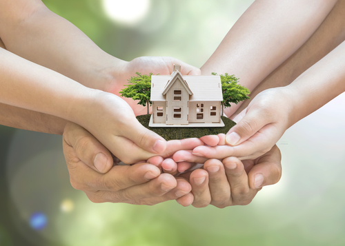 Image of hands holding a wooden house with trees