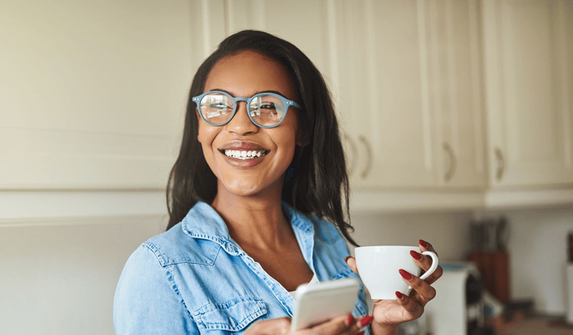 customer smiling holding a mug and a phone