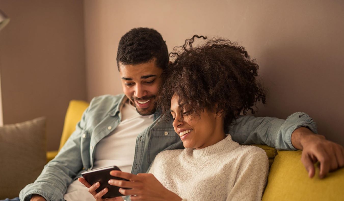 couple sat on sofa looking at tablet